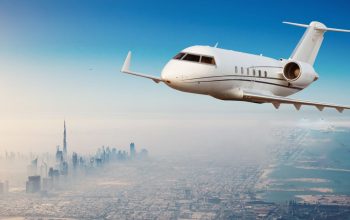 Private jet plane flying above Dubai city in beautiful sunset light. Modern and fastest mode of transportation, business life.