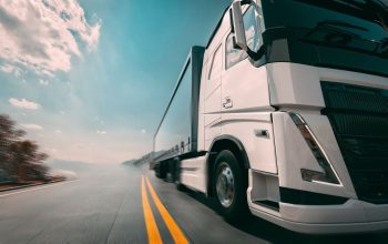 A large white truck is traveling on the highway in a left-to-right direction. The sky behind is bright blue.3d, rendering, illustration,-